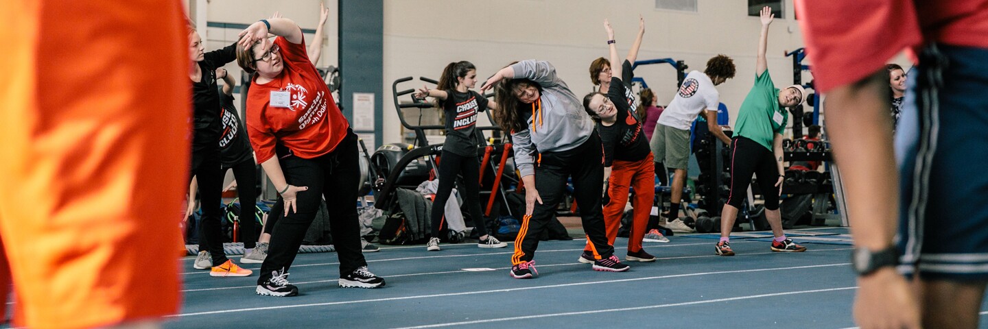 A group of athletes working out in a gym doing side bends.