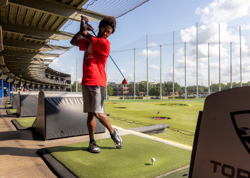 An athlete taking a swing at Topgolf. 