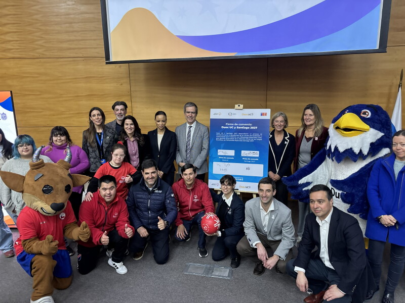 People both kneeling and smiling in a group posing for a photo alongside two mascots (bird and bull)