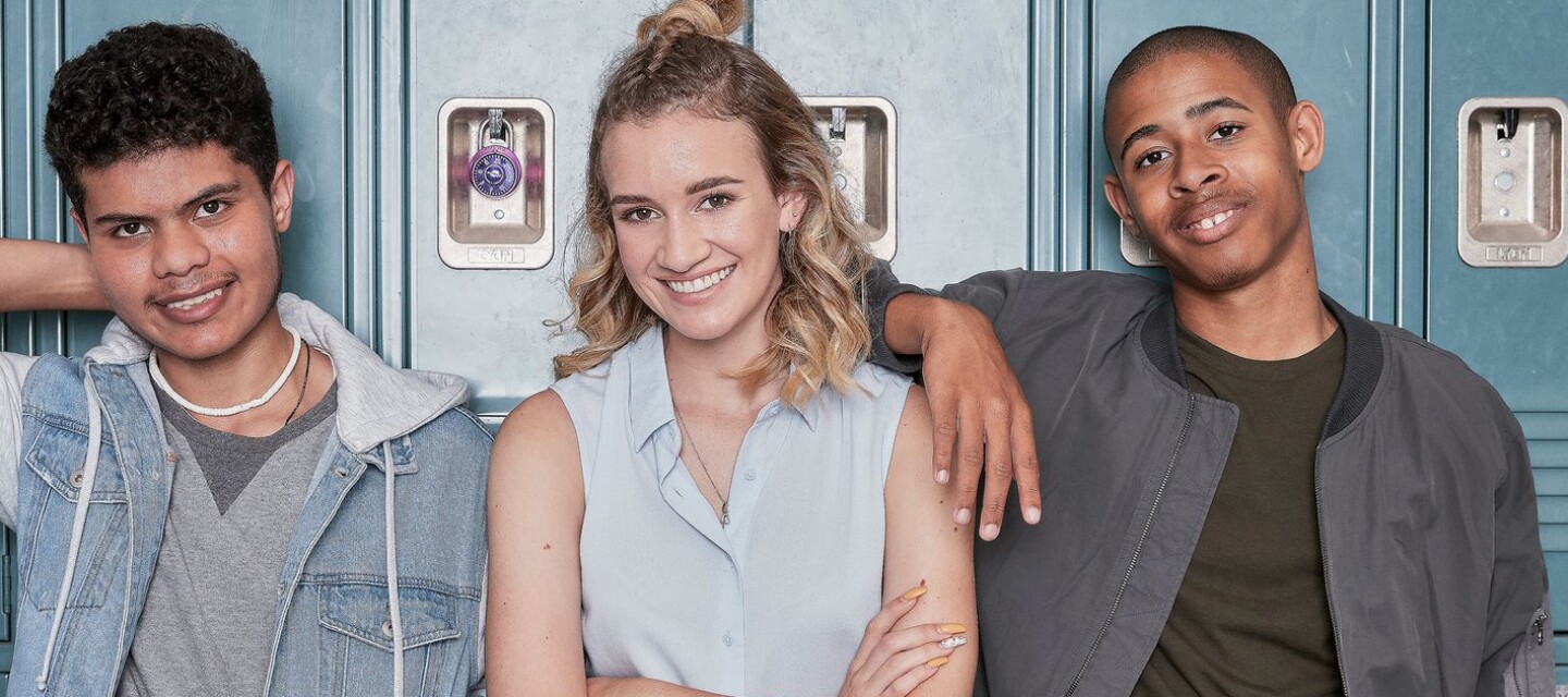 Three young adults standing in front of lockers