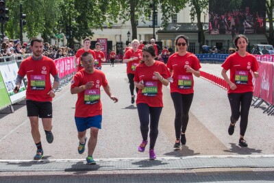 Runners in red t-shirts running towards the camera across a finish line. 