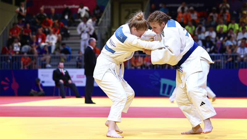 Two judo athletes with their arms entwined during match.