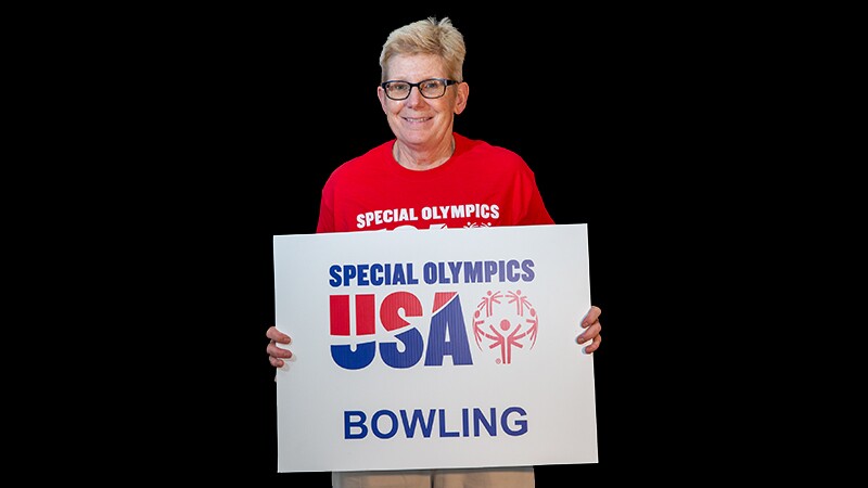 Cindy Schopper holding a sign that reads: Special Olympics USA Bowling