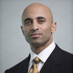 Ambassador Yousef Al Otaiba in a dark suite, white shirt, and yellow,gold, and black striped tie.