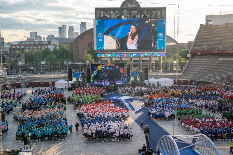 Demi Lovato performs on stage during the 2026 Special Olympics USA Games Opening Ceremony at Huntington Bank Stadium in Minneapolis. Athletes from delegations across the United States gather on the field in colorful team uniforms while the Minneapolis skyline rises in the background.