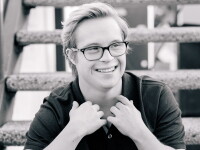 Cole sitting on a set of stairs looking into the distance and smiling. 