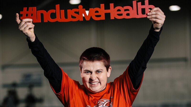Athlete holding up a sign that reads: #InclusiveHealth