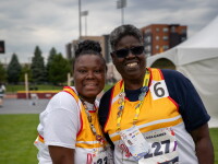 Two Special Olympics Maryland athletes in team uniforms smile and embrace on a grassy competition field after competing in Mini Javelin at the 2026 USA Games.