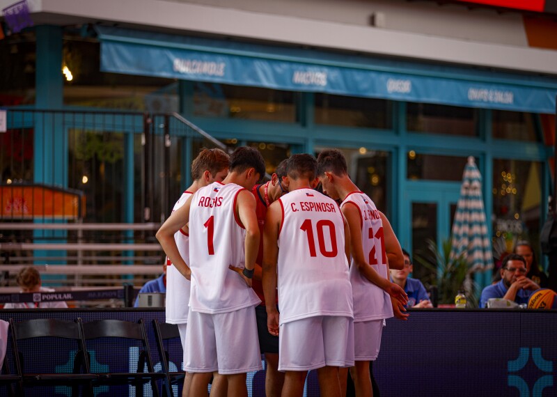 A basketball team is huddled together courtside