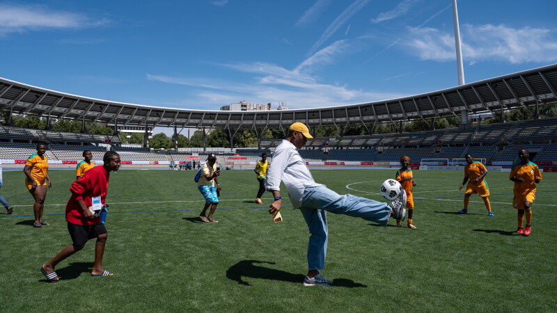 A man kicks a football with a group of football players