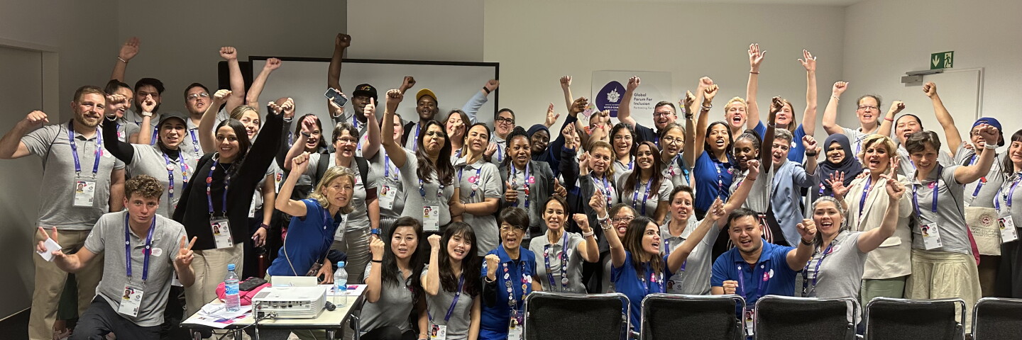 A group of adults in a classroom setting standing in two rows for a group picture. 