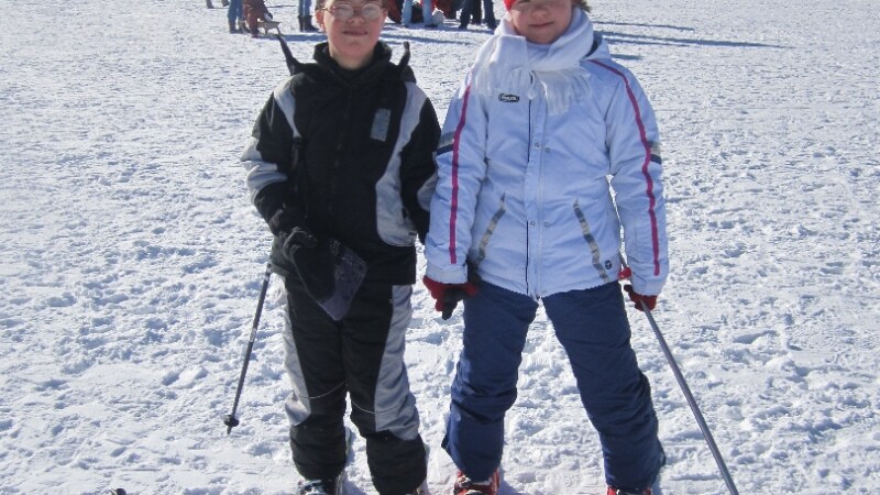 Un niño y una niña posando en esquís en la nieve.