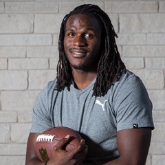 Jamaal Charles in a gray puma t-shirt holding an American football.