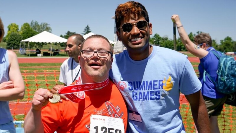 A man has his arm around the shoulder of an athletes that's showing off his medal. 