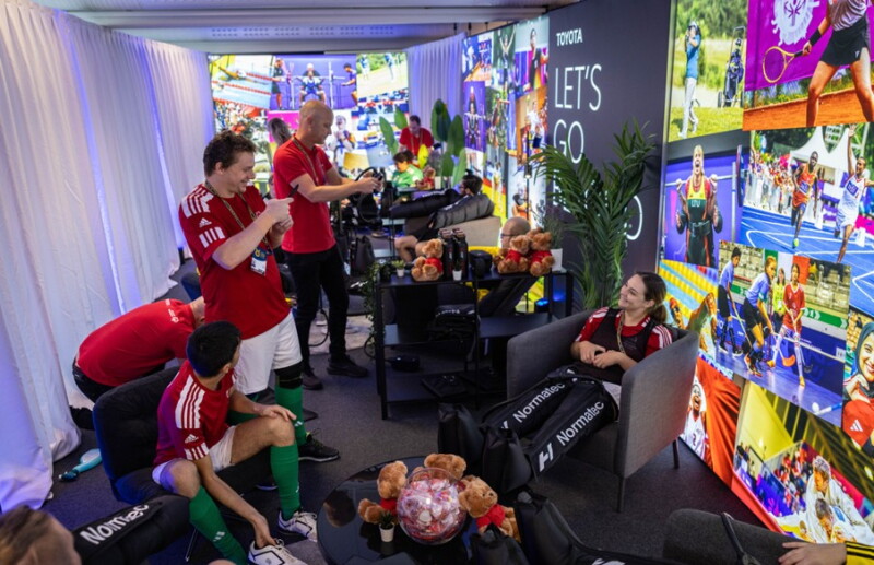 Athletes in a room, talking and interacting with one another. 