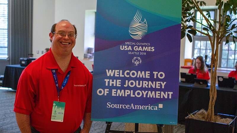 David Egan stands next to a SourceAmerica sign at the 2018 USA Games in Seattle.