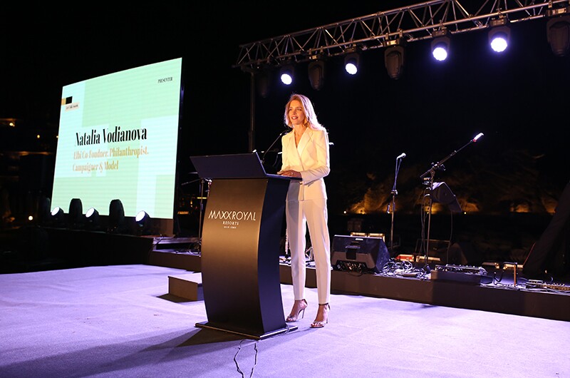 Natalia Vodianova on stage at the awards speaking behind a podium.