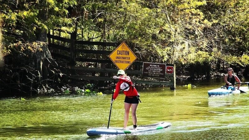 Special Olympics athlete stands up on paddleboard. 