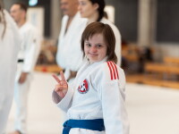A young woman wearing a judogi and making a peace sign