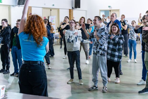 A group of people stood up doing a stretching exercise