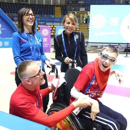A group of four people, one of who is in a wheelchair, all smiling brightly