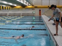 Young man swimming toward a coach at the end of the pool. 