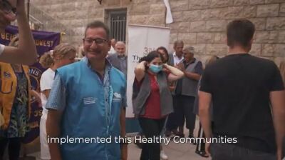 Man outside smiling, people in the background. 