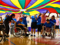 A group of athletes waving a huge, colourful cloth over their heads