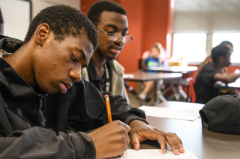 Two students working on an assignment at a desk. 