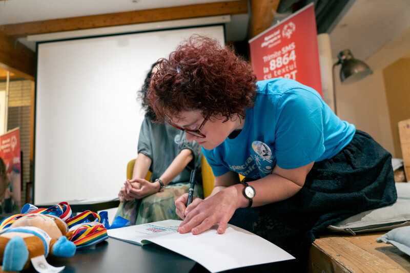 A woman signs an open book. 