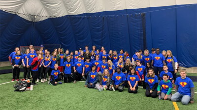 A group of young adults sitting together in an indoor football stadium for a group photo. 