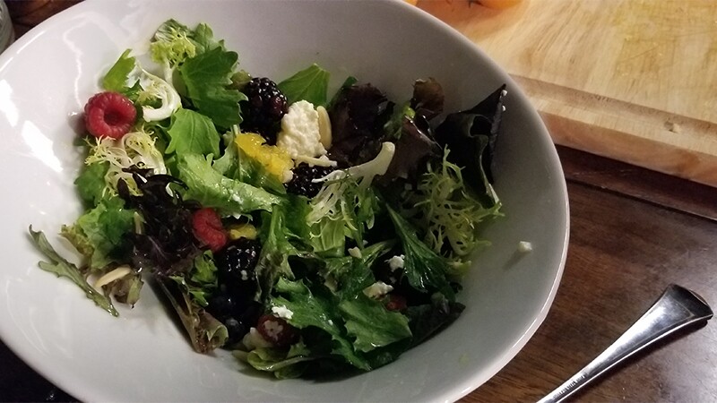Salad in a white bowl sitting on a table.