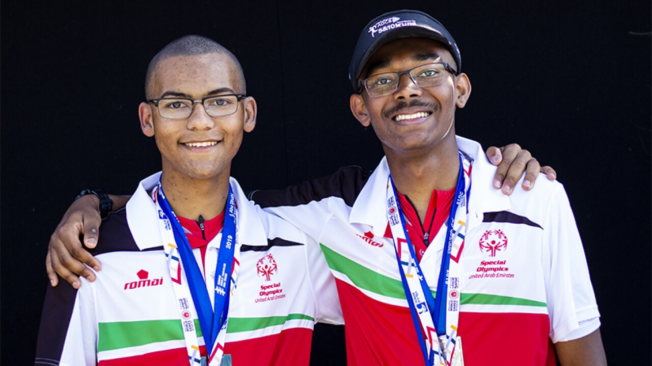 Michael and Jonah Hambleton standing with their arms around one another both with credentials around their necks.