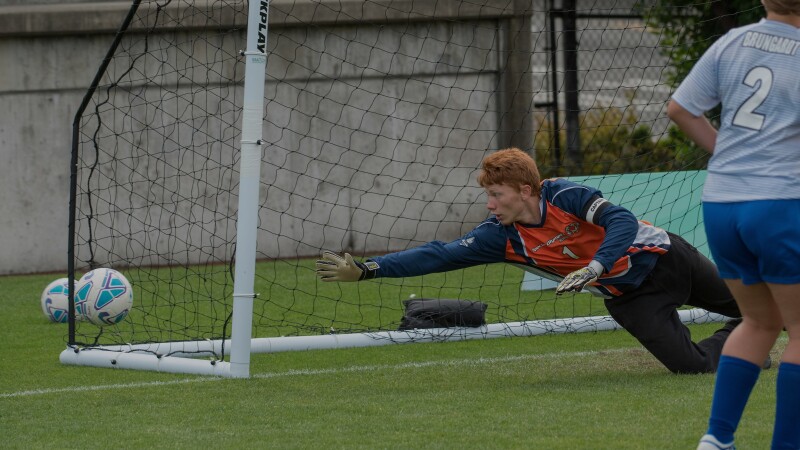 keeper diving for the ball before it makes it into the net.