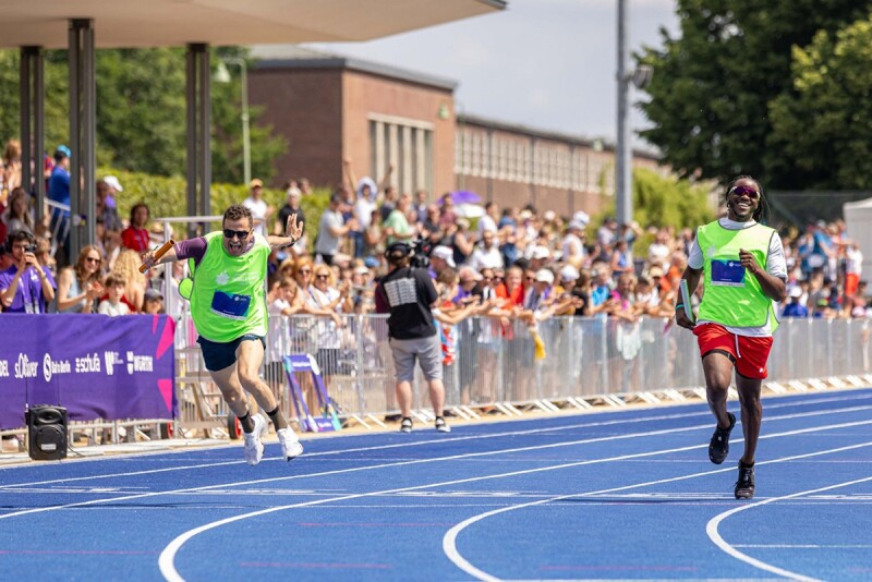Athletes running on track with batons