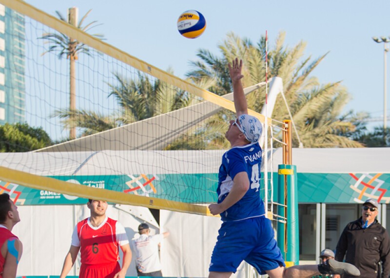 Beach Volleyball player jumping to spike the ball.