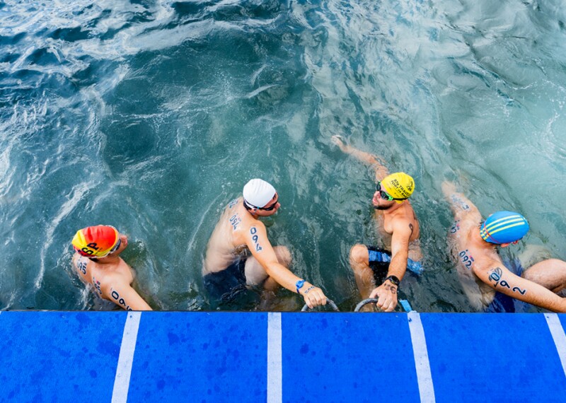 Six swimmers at the starting line of an open water swimming competition. 
