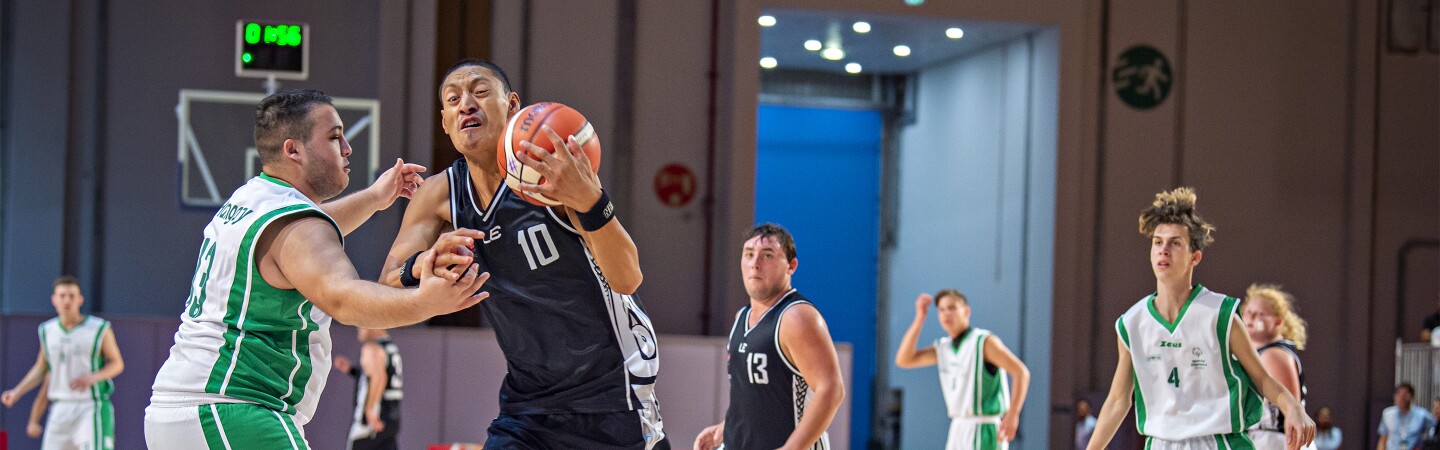 Eight young men playing basketball in a competition.