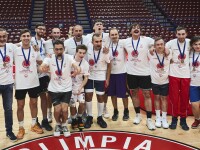 A group large of basketball players stand together smiling on court.