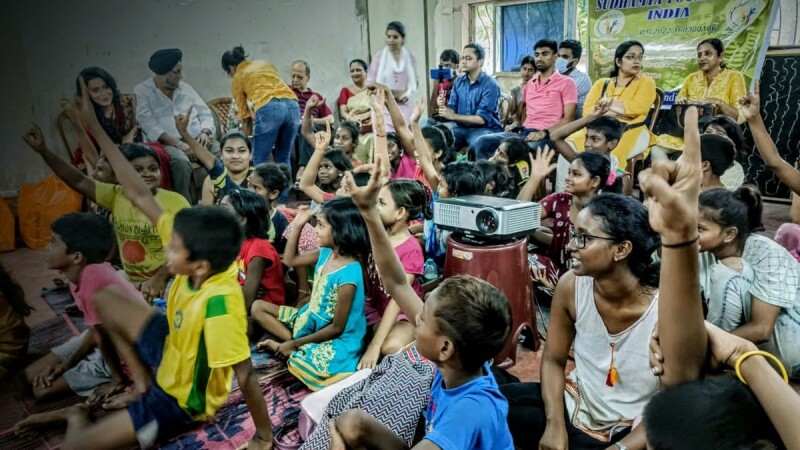 Children in the classroom raise their hands. 