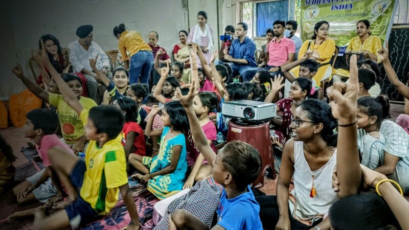 Children in a classroom raising their hands. 