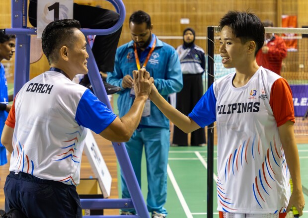 A coach and an athlete holding hands in mid air