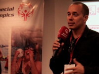Arroyo holding a red microphone in front of a screen, talking passionately.