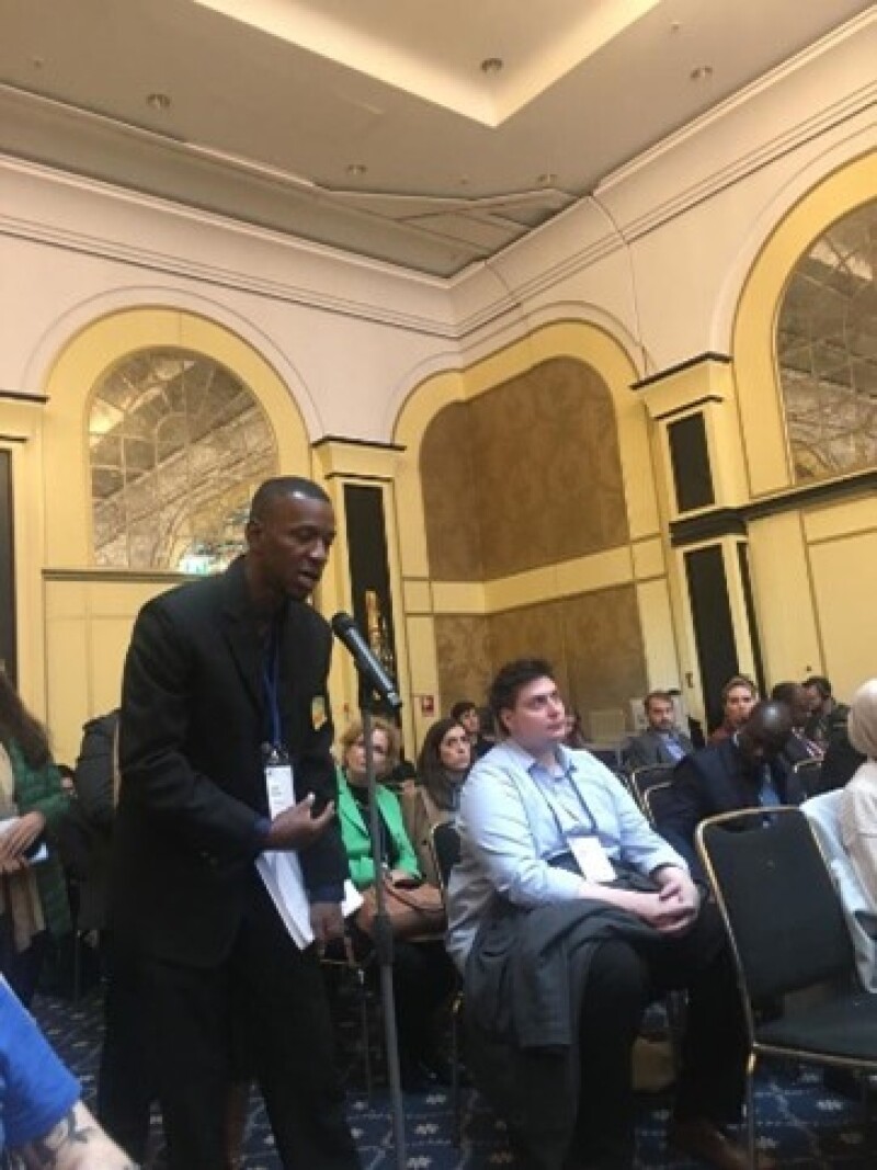 Special Olympics Jamaica Health Messenger David Duncan stands at a microphone to ask a question.