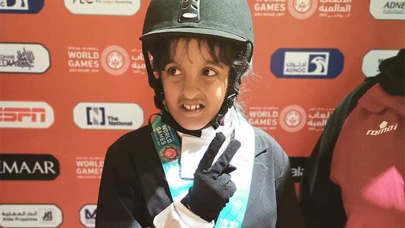 Sara Mashabek giving the peace sign in her equestrian outfit.