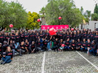 A group of 110 people with black shirts with the text “Special” pose with red footballs, against a red banner with the Special Olympics logo in white.