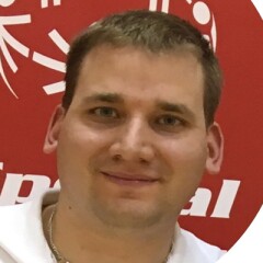 Adam Hammer smiling in front of a backdrop of the Special Olympics logo.