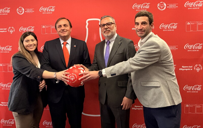 Four people posing for a photo while holding a Special Olympics-branded football.