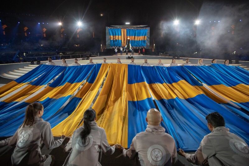 A group of volunteers holding Sweden's flag on stage during the closing ceremony.