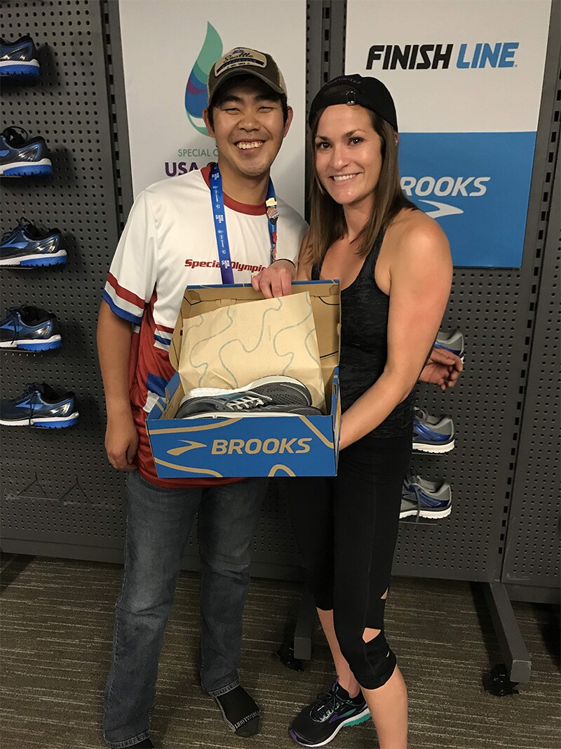 Finish Line Youth Foundation employee presents a Special Olympics athlete with a new pair of shoes.